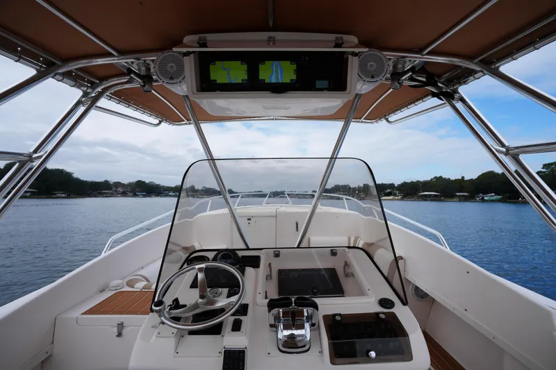 Slide: The Image of 1999 Intrepid 366 boat cockpit with steering wheel and navigation screens on a calm lake. - 17