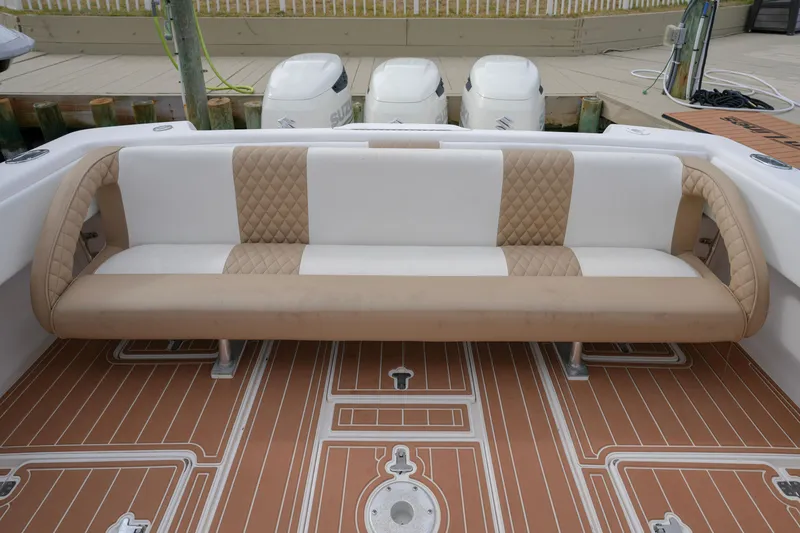 Slide: The Image of 1999 Intrepid 366 boat with tan and white seating, wooden deck, and Suzuki outboard motors. - 32