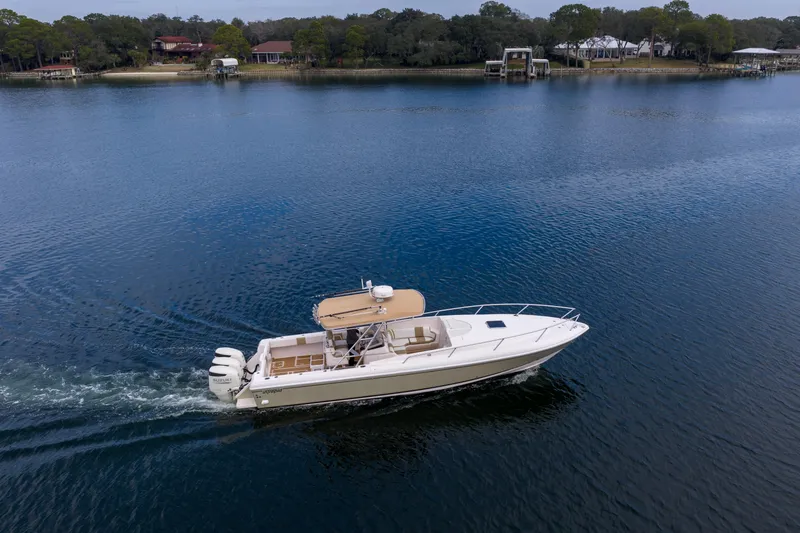 Slide: The Image of 1999 Intrepid 366 boat cruising on a serene lake with scenic shoreline. - 34