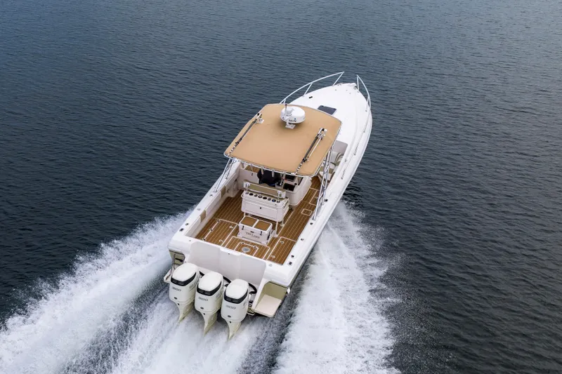 Slide: The Image of 1999 Intrepid 366 boat cruising on open water, rear view with triple engines. - 40