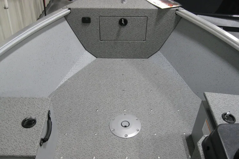 Slide: The Image of 2025 Lund 1800 Alaskan SS boat interior with gray textured flooring and storage compartments. - 10