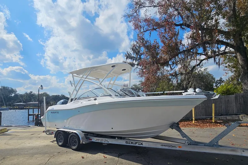 Slide: The Image of 2022 Sea Fox 226 Traveler boat on trailer, parked near a scenic waterfront. - 1