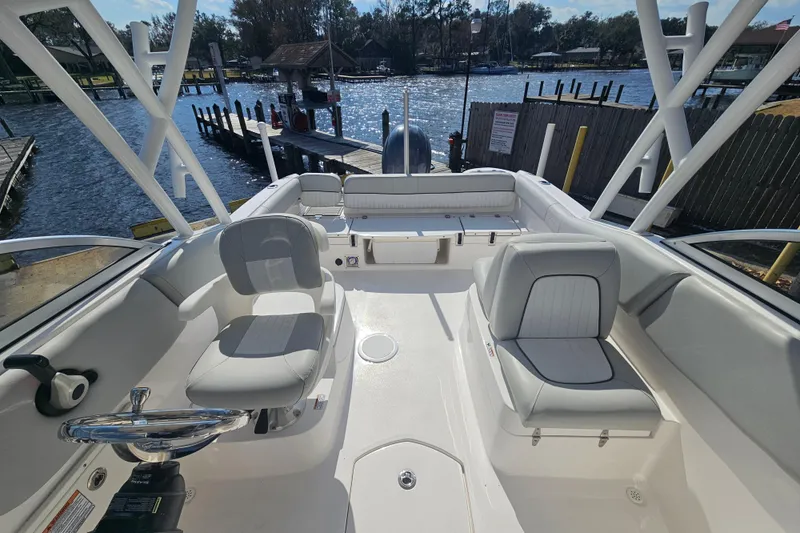 Slide: The Image of 2022 Sea Fox 226 Traveler boat interior with seating and storage, docked by a scenic waterfront. - 10