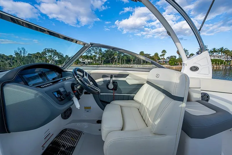 Slide: The Image of 2019 Cobalt 23SC boat interior with steering wheel and seating, under a clear blue sky. - 10