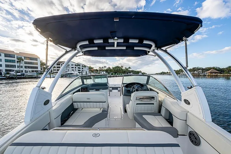 Slide: The Image of 2019 Cobalt 23SC boat interior with seating, steering wheel, and canopy on a scenic waterway. - 12