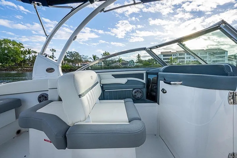 Slide: The Image of 2019 Cobalt 23SC boat interior with white and gray seating, under a blue sky. - 17