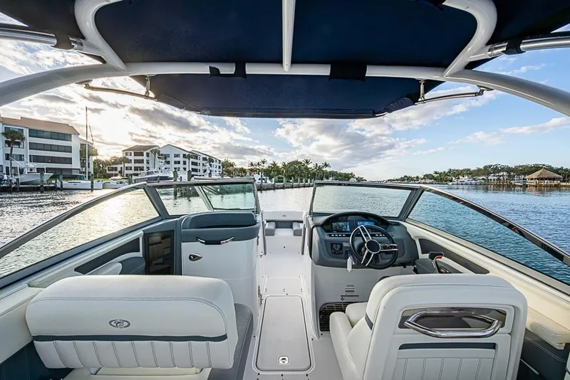 Slide: The Image of 2019 Cobalt 23SC boat interior with steering wheel, dockside view, and blue canopy. - 8