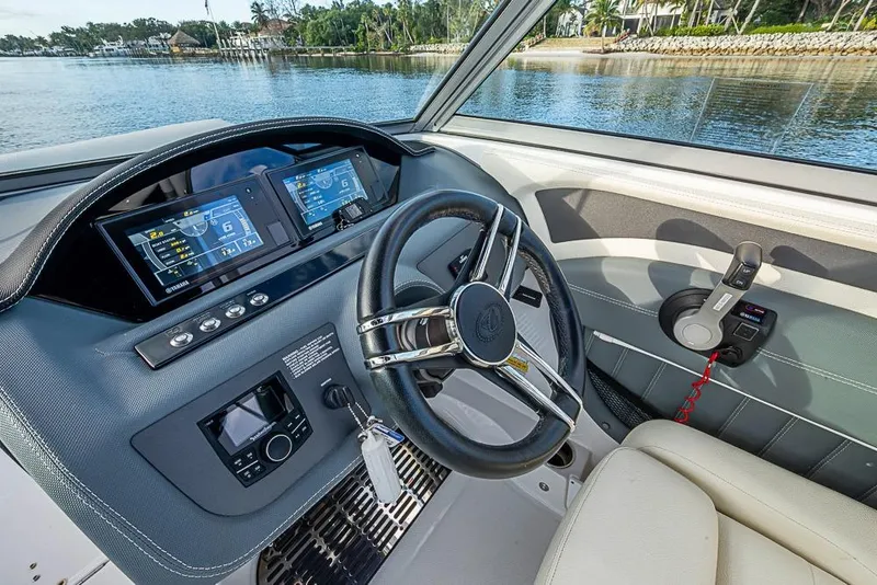 Slide: The Image of 2019 Cobalt 23SC boat dashboard with steering wheel and digital displays on a scenic lake. - 9
