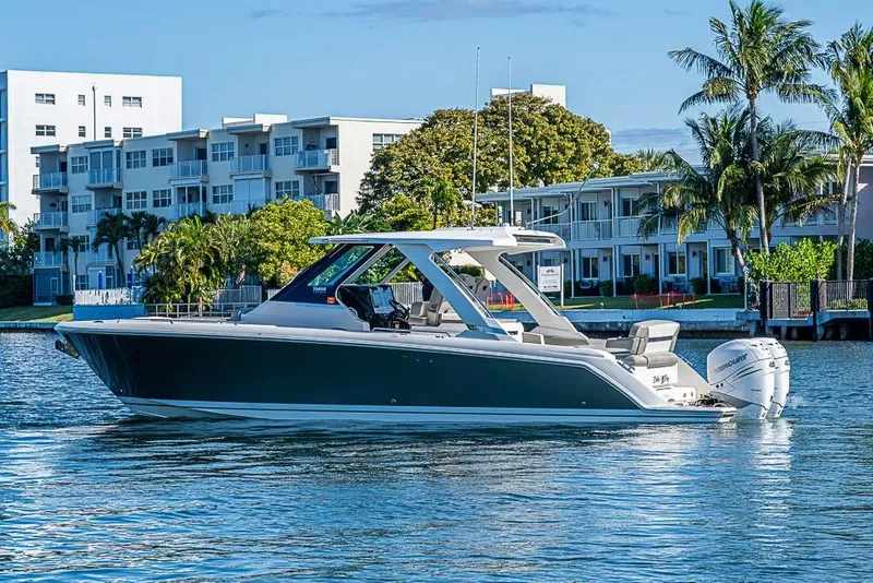 Slide: The Image of 2023 Tiara Yachts 34 LS boat on water, with modern buildings and palm trees in background. - 10