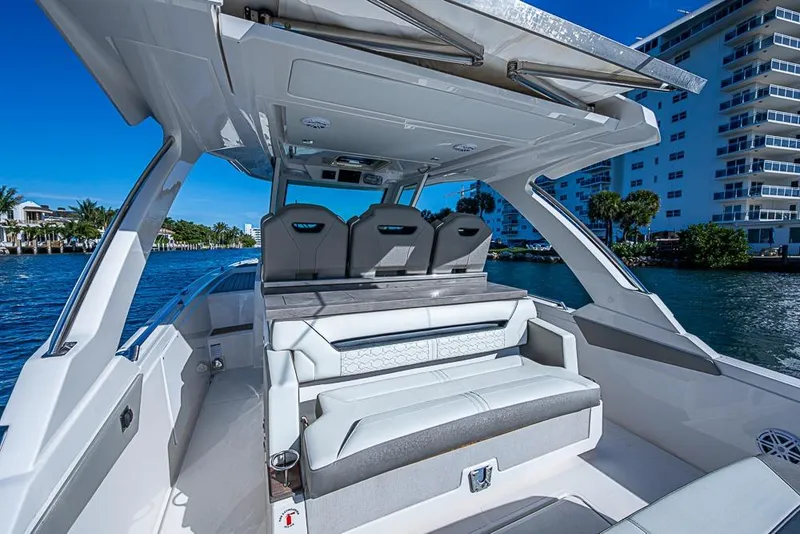 Slide: The Image of 2023 Tiara Yachts 34 LS luxury boat interior with seating, docked by waterfront buildings. - 32