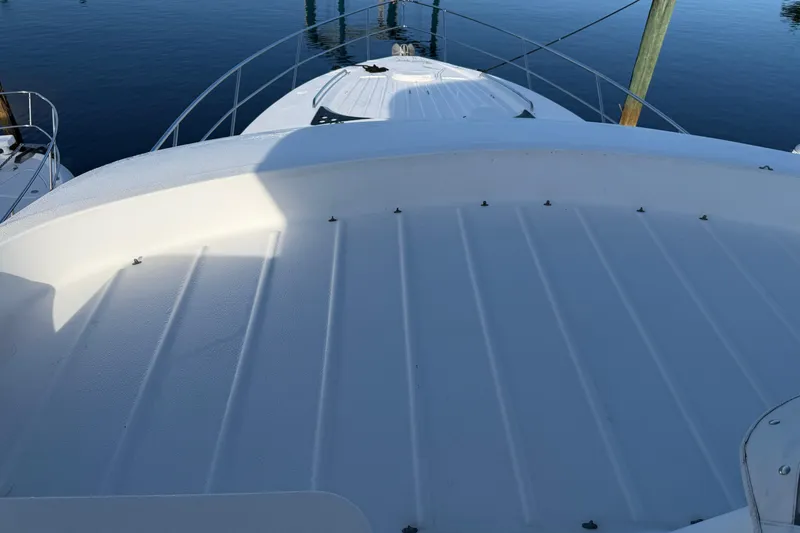 Slide: The Image of 2006 Neptunus 56 Flybridge yacht deck, featuring sleek design and railing, docked on calm water. - 60