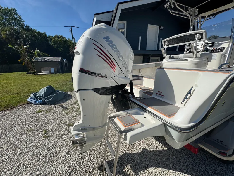Slide: The Image of 2019 Mako 214C boat with Mercury outboard motor, parked on gravel near a house. - 15