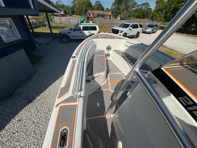 Slide: The Image of 2019 Mako 214C boat parked on gravel driveway with vehicles in the background. - 35