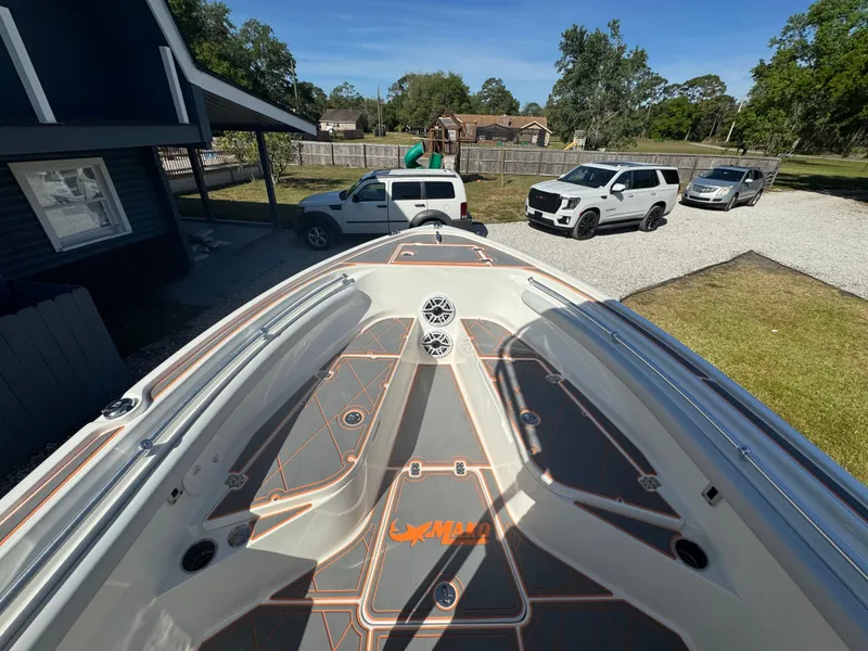 Slide: The Image of Bow view of 2019 Mako 214C boat with parked vehicles in the background. - 36