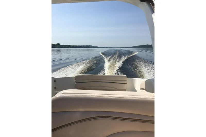 Slide: The Image of 2004 Larson Cabrio 260 boat cruising on a calm lake, leaving a wake behind. - 3