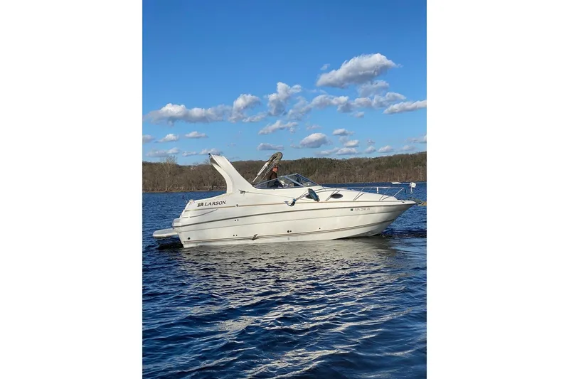 Slide: The Image of 2004 Larson Cabrio 260 boat on a lake under a clear blue sky. - 4