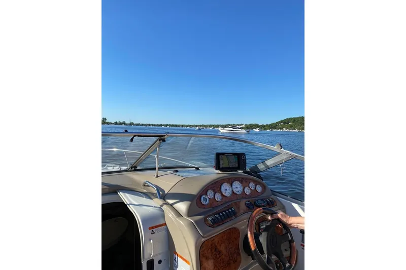 Slide: The Image of 2004 Larson Cabrio 260 boat dashboard with scenic lake view and clear blue sky. - 5