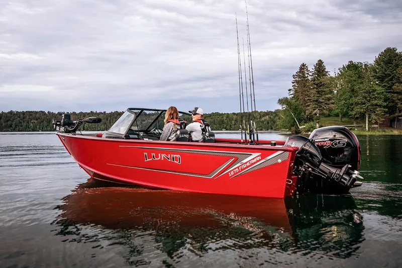 Slide: The Image of Manufacturer Provided Image: 2025 Lund 1875 Fisherman boat on a serene lake, featuring a vibrant red design. - 24