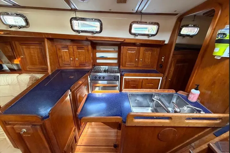 Slide: The Image of Interior of 2001 Tartan 3700 sailboat kitchen with wooden cabinetry and blue countertops. - 19