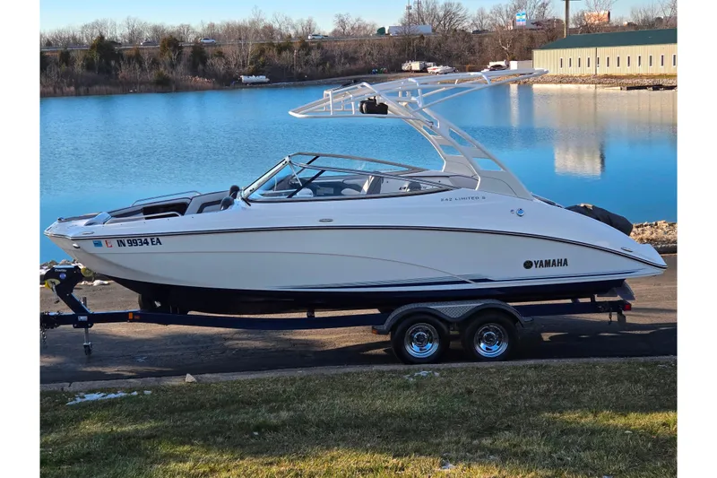 The Image of 2017 Yamaha Boats 242 Limited S E-Series on trailer by a lake. - 0