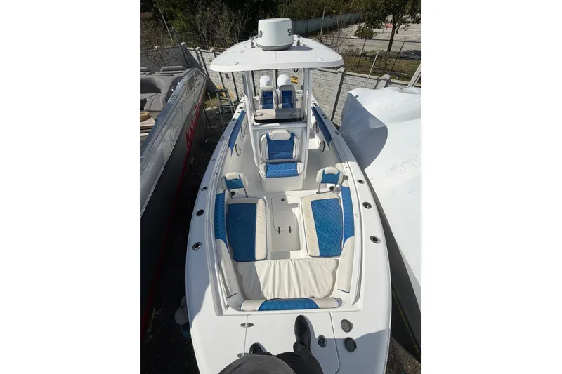 Slide: The Image of 2015 Sea Hunt Gamefish 25 boat with blue and white seating, docked outdoors. - 4