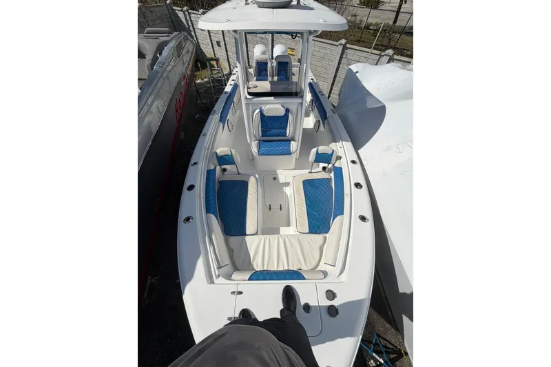 Slide: The Image of 2015 Sea Hunt Gamefish 25 boat with blue and white seating, docked outdoors. - 5