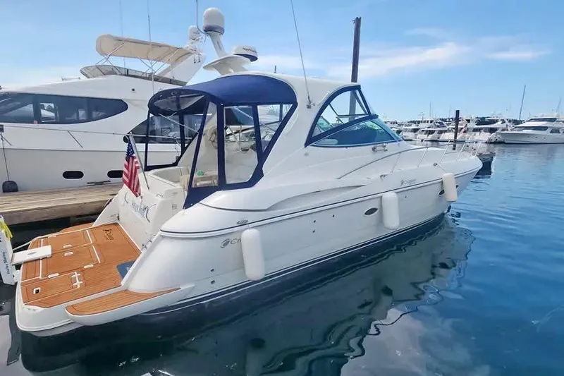 The Image of 2005 Cruisers Yachts 440 Express docked in a marina, featuring sleek design and American flag. - 0