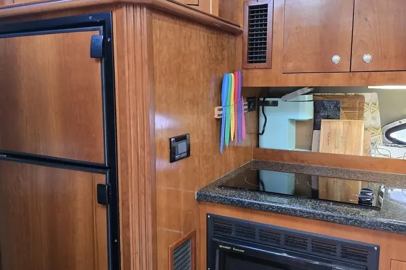 Slide: The Image of 2005 Cruisers Yachts 440 Express kitchen with wooden cabinetry and modern appliances. - 12