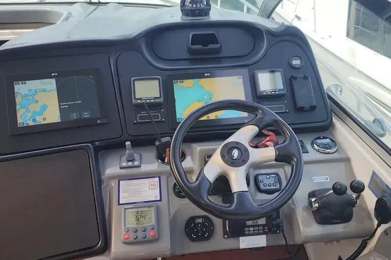 Slide: The Image of 2005 Cruisers Yachts 440 Express helm with navigation screens and steering wheel. - 7
