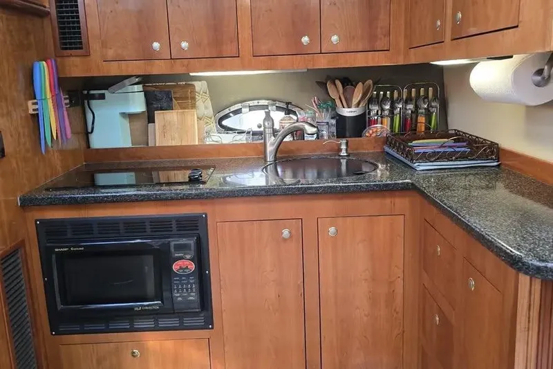 Slide: The Image of 2005 Cruisers Yachts 440 Express kitchen with wooden cabinets, sink, and microwave. - 11