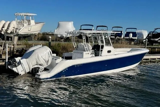 The Image of 2023 Edgewater 340CC boat with blue hull docked in marina. - 0