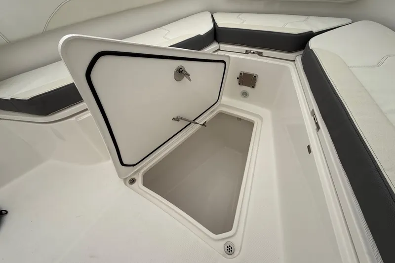 Slide: The Image of 2023 Edgewater 340CC boat storage compartment with open hatch and cushioned seating. - 11