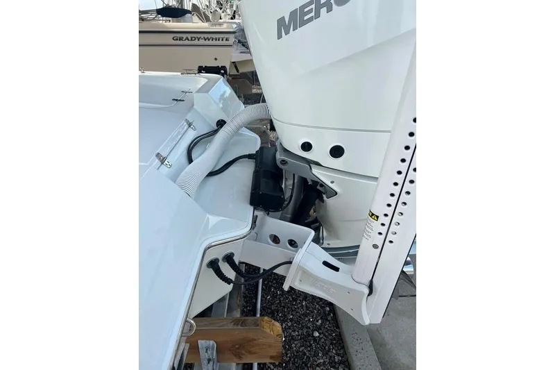 Slide: The Image of 2025 Contender 26 Bay boat with Mercury engine and power pole, docked on gravel. - 20