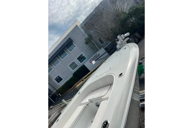 Slide: The Image of 2025 Contender 26 Bay boat parked outside a modern building under cloudy skies. - 8