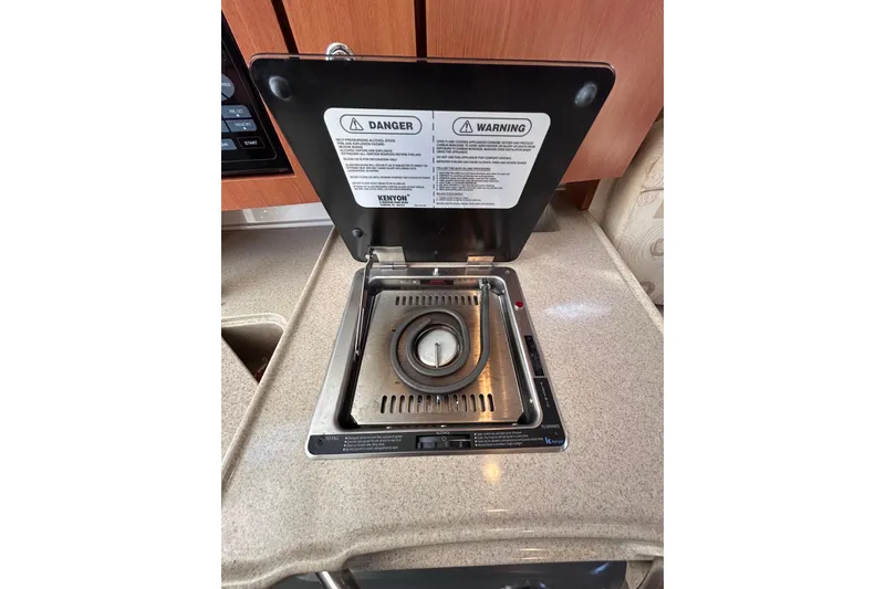 Slide: The Image of 2006 Wellcraft 290 Coastal stove in cabin, featuring safety warnings and sleek design. - 14