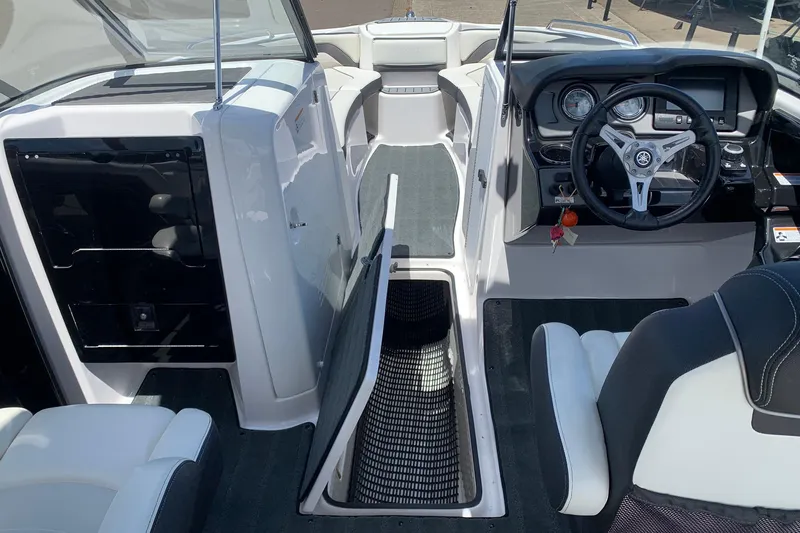 Slide: The Image of 2016 Yamaha Boats 242 Limited interior with steering wheel and open storage compartment. - 7