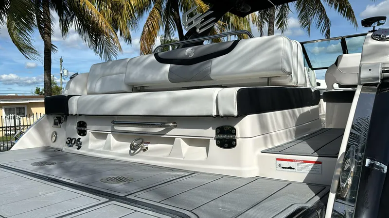 Slide: The Image of 2021 Chaparral 30 Surf boat with white seating, docked under palm trees. - 7