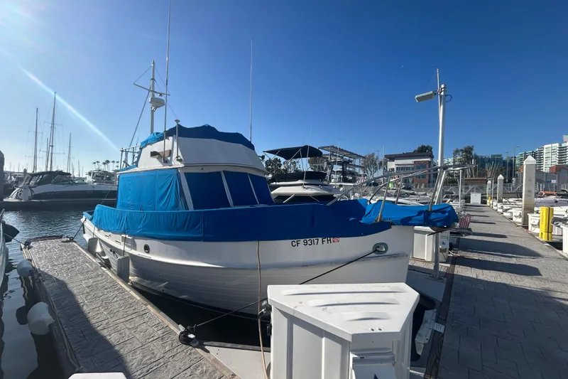 The Image of 1973 Grand Banks 32 Sedan cruising in a marina under clear blue skies. - 0