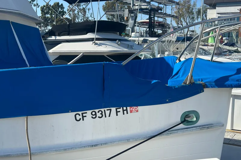 Slide: The Image of Man standing on 1973 Grand Banks 32 Sedan boat deck, sunny marina background. - 2