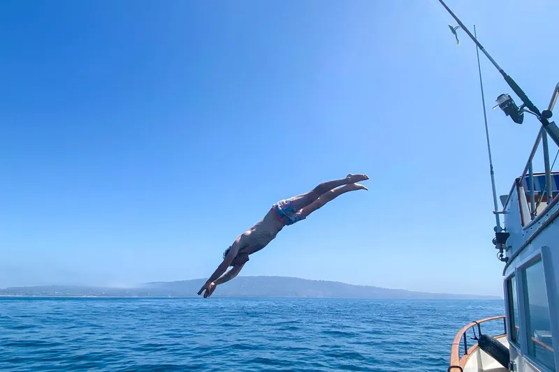 Slide: The Image of Man diving off 1973 Grand Banks 32 Sedan into the ocean on a sunny day. - 32