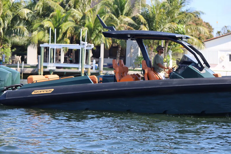 Slide: The Image of 2025 Skipper-BSK 38 boat cruising on water with palm trees in the background. - 12