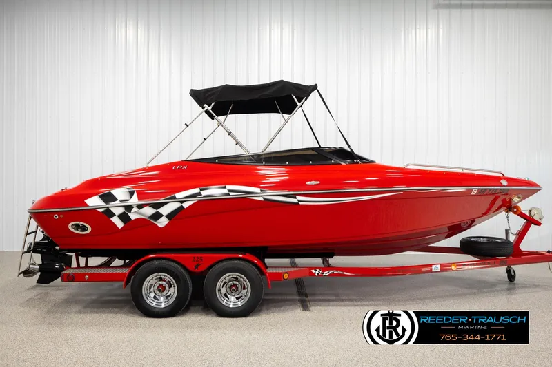 Slide: The Image of 2005 Crownline 225 LPX boat, vibrant red with checkered flag design, on trailer in showroom. - 5