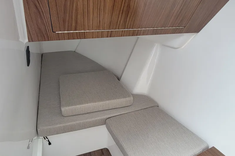 Slide: The Image of Interior cabin of 2026 Four Winns H33 OB boat with cushioned seating and wooden accents. - 15