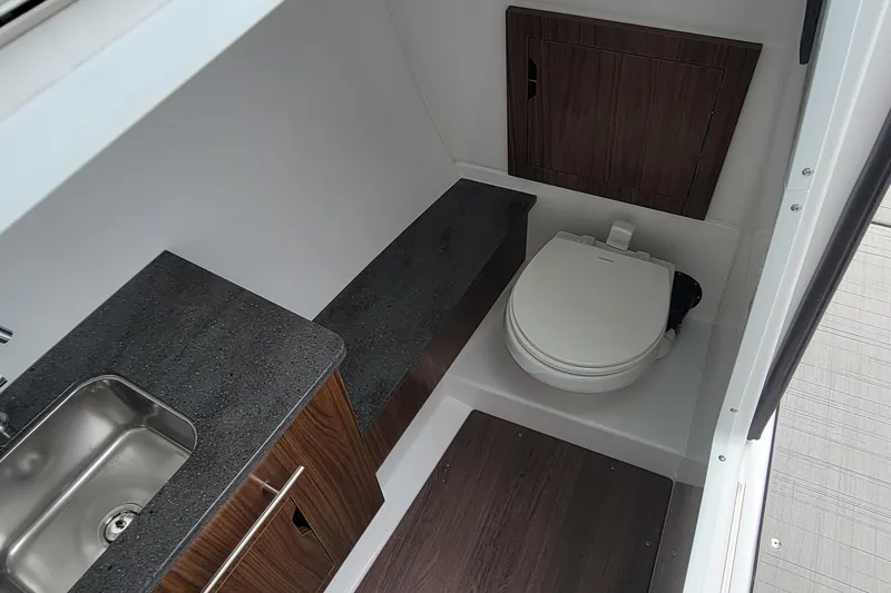 Slide: The Image of 2026 Four Winns H33 OB boat bathroom with sink, toilet, and wood accents. - 17