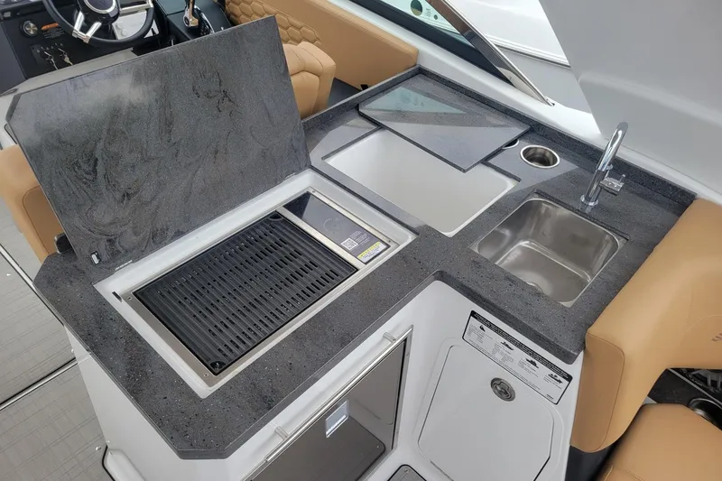 Slide: The Image of 2026 Four Winns H33 OB boat kitchen with grill, sink, and countertop. - 21