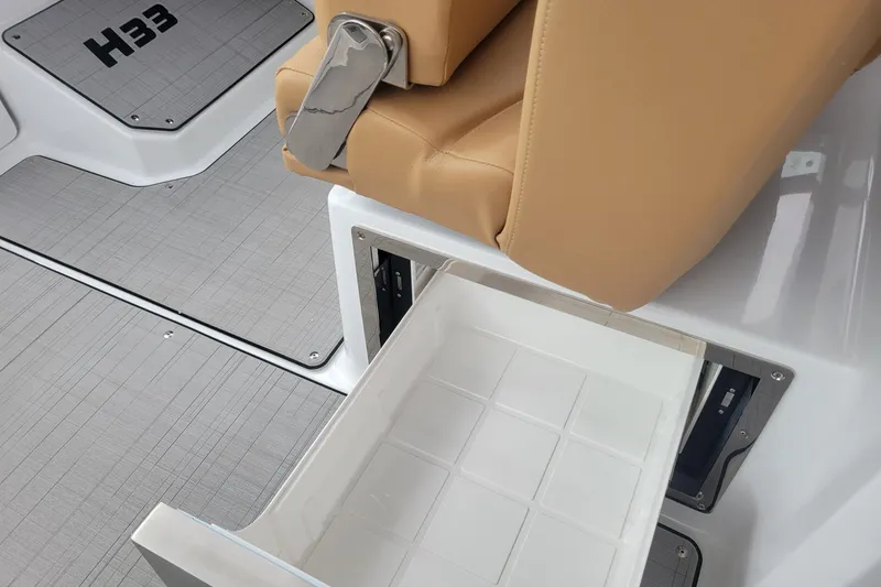 Slide: The Image of 2026 Four Winns H33 OB boat interior with storage drawer and tan seating. - 24