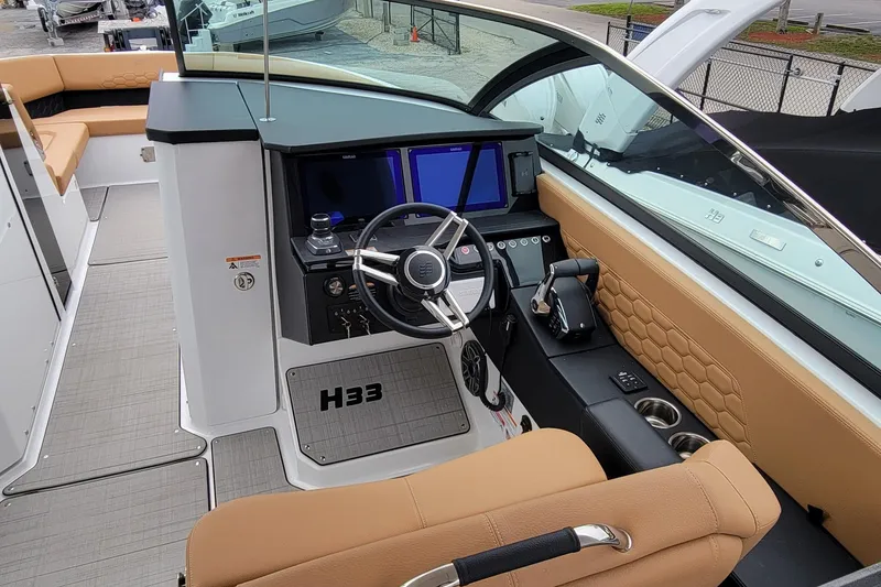 Slide: The Image of 2026 Four Winns H33 OB boat interior with modern dashboard and tan seating. - 7