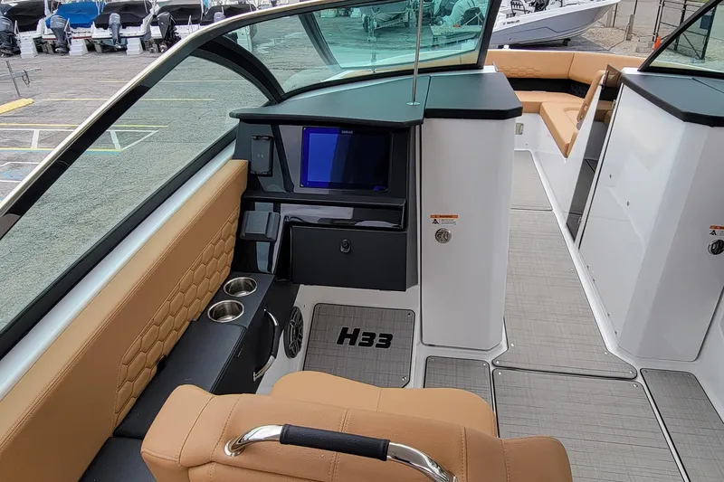Slide: The Image of Interior of 2026 Four Winns H33 OB boat with tan seating and modern dashboard. - 8