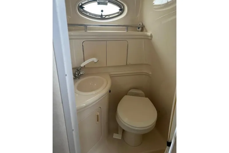 Slide: The Image of 2003 Sea Ray Sundancer 280 bathroom with sink, toilet, and porthole window. - 10