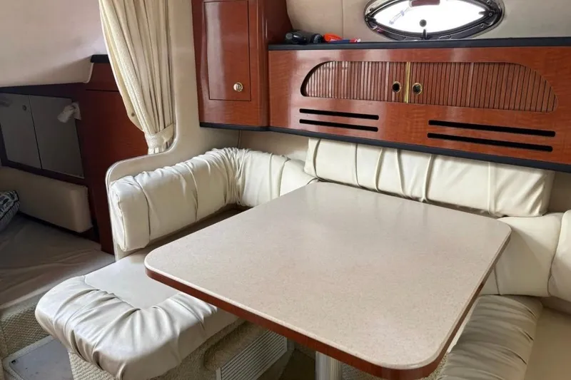 Slide: The Image of 2003 Sea Ray Sundancer 280 interior with cushioned seating and wooden cabinetry. - 8